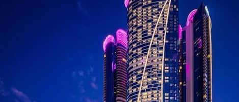 A high-rise building with a distinctive curved facade, multiple balconies, and illuminated signage.