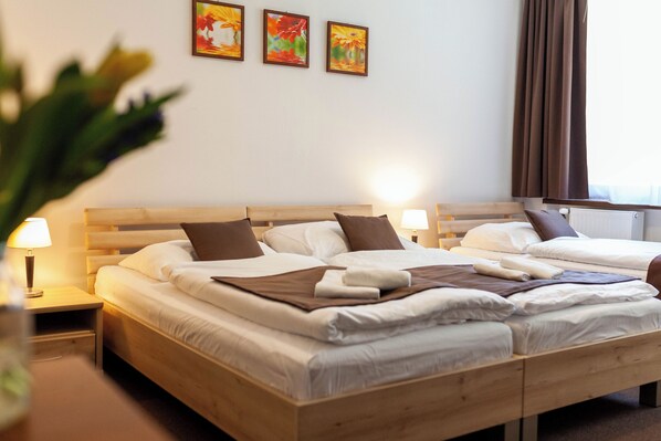 A double bed with a wooden headboard, two bedside tables with lamps, and three framed floral paintings on the wall. - Lopušná dolina Resort (Lučivná)