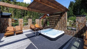 A wooden deck with a hot tub, lounge chairs, and a pergola. - Lopušná dolina Resort (Lučivná)