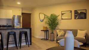 A modern kitchen with a refrigerator, bar stools, and a dining area with a table and chairs. - w Exceptional 1BR w Balcony in San Isidro (Lima)