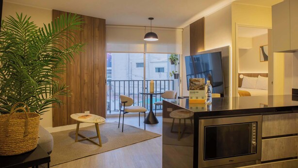 A modern kitchen with a built-in microwave, a dining area with a round table and chairs, and a large potted plant. - w Exceptional 1BR w Balcony in San Isidro (Lima)