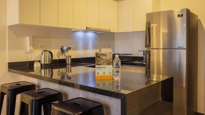 A modern kitchen with stainless steel appliances, a black countertop, and a water bottle on the counter. - w Exceptional 1BR w Balcony in San Isidro (Lima)
