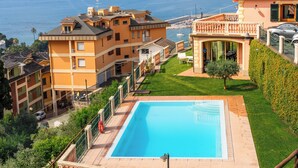 A large rectangular swimming pool with a clear blue poolside area, surrounded by a well-maintained lawn and a hedge. - Charming 3-bedroom 4 bathrooms villa with WiFi and AC in beautiful Rapallo (Rapallo)