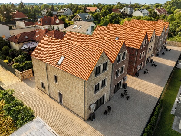 A multi-story building with a red-tiled roof, a courtyard with outdoor seating, and a brick facade. - Apart House A4 (Bielany Wrocławskie)