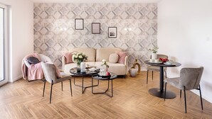 Een moderne woonkamer met een behang, een bank, twee fauteuils, een salontafel en een bijzettafeltje met decoratieve objecten.