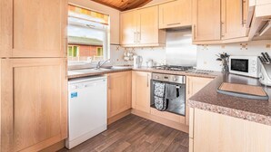 A modern kitchen with wooden cabinets, a stainless steel stove, a dishwasher, and a microwave. - Wonderful private villa for 4 guests with WIFI, TV, balcony and pets allowed (Ballingry)
