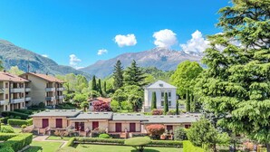 Um hotel com vários edifícios, um jardim bem cuidado e montanhas ao fundo.