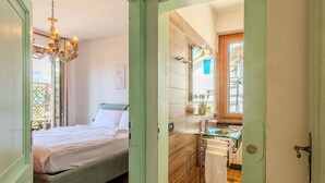 Quarto com cama, lustre e vista para o exterior.