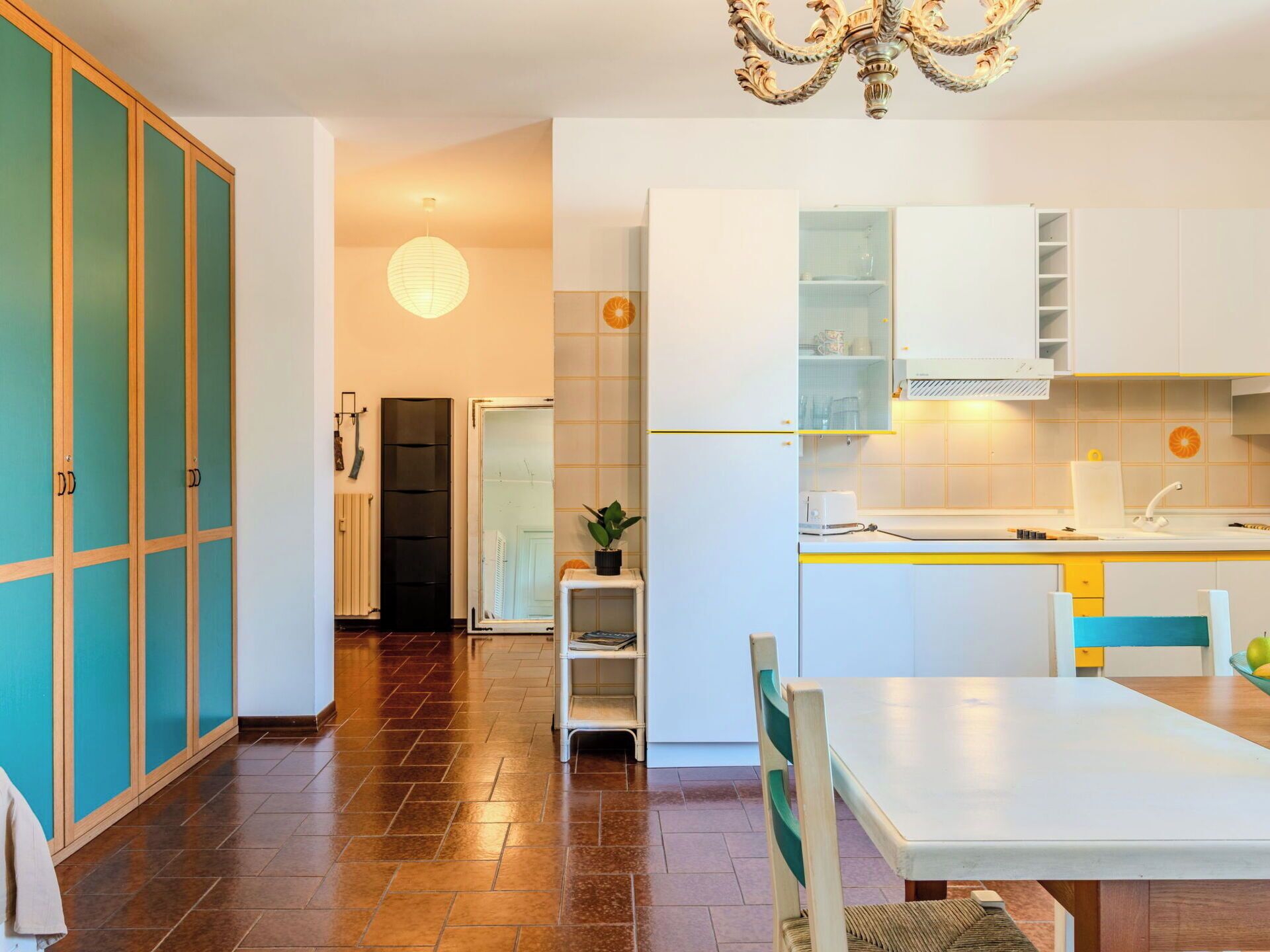A modern kitchen with white cabinets, a dining table, and a chandelier.