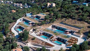 An aerial view of a residential area with multiple houses, swimming pools, and solar panels. - 2S Villas Resort - cave villas - Villa Epsilon E - Luxury Comfort Stay (Sivota)