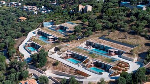 An aerial view of a residential area with multiple houses, swimming pools, and solar panels.
