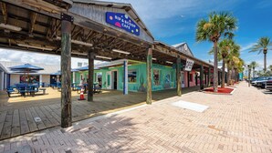 A waterfront area with a wooden deck, outdoor seating, and a sign for a 'Sip & Scoop Cafe'.