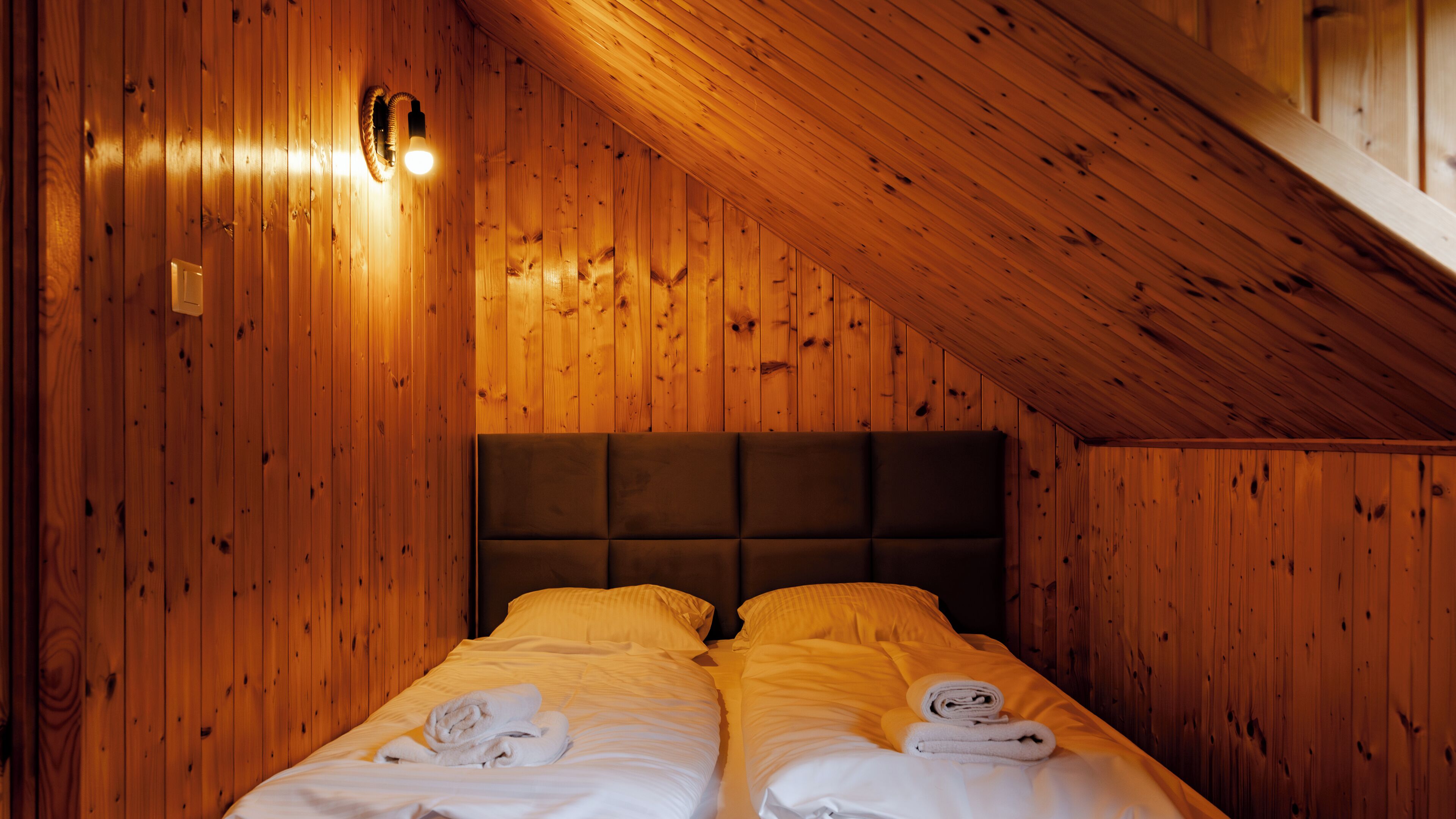A wooden room with a bed, two pillows, and a headboard.