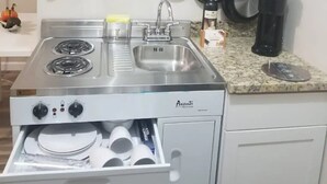 A compact kitchen with a stove, sink, and microwave. - estudio proyector (Marietta)