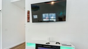 Ein modernes Wohnzimmer mit Flachbildfernseher an der Wand, einer integrierten Unterhaltungseinrichtung inklusive Spielkonsole und einem Kamin.
