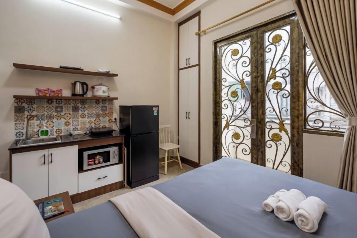 Habitación de hotel con cama, kitchenette y vistas a través de una puerta decorativa.