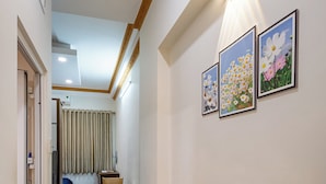 A hallway with a dining area, featuring a wooden table and chairs, a ceiling light, and framed floral artwork on the wall. - Hearth and Home De Tham (Ho Chi Minh City)
