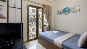 A bedroom with a bed, a TV, a wardrobe, and a decorative wall piece. - Hearth and Home De Tham (Ho Chi Minh City)