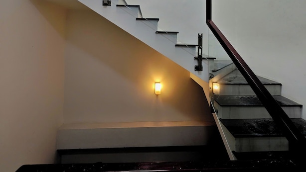 A modern staircase with a glass railing and a wall-mounted light fixture. - Hearth and Home De Tham (Ho Chi Minh City)