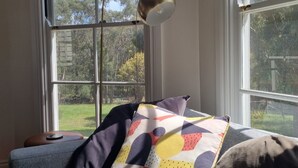 Una habitación con un ventanal grande, un cojín estampado y una lámpara.