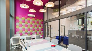 Una sala conferenze moderna con un design di parete esagonale dai colori vivaci, tavoli e sedie bianche.