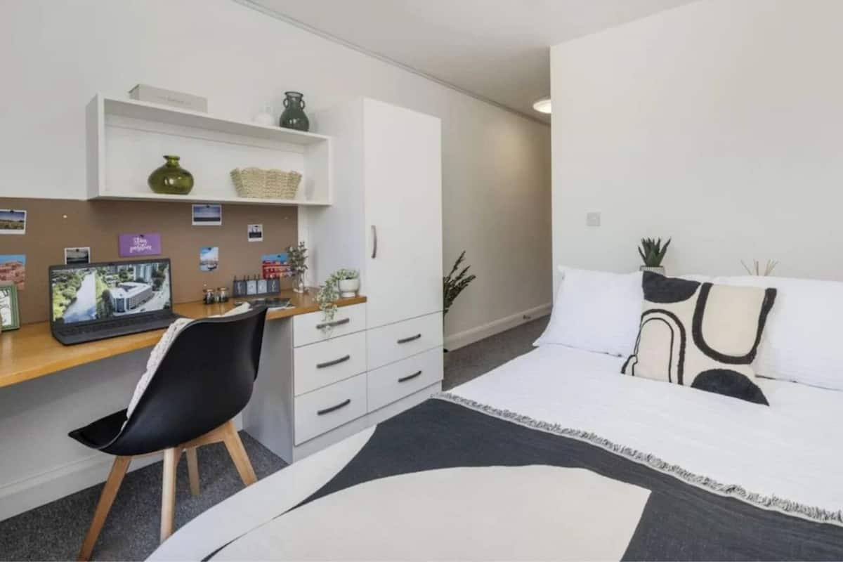 A modern bedroom with a bed, a desk, and a chair.