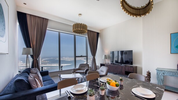 Una sala de estar moderna con un ventanal grande, una mesa de comedor con frutero y un sofá.
