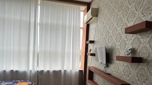 A room with a bed, a TV mounted on a wall, and a window with curtains. - Arena Hotel Imishli (Imishli)