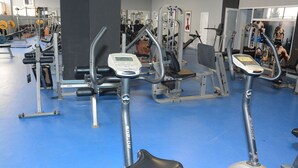 A gym with cardio equipment, weight machines, and a blue floor. - Arena Hotel Imishli (Imishli)