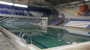 An indoor swimming pool with a diving platform and seating area. - Arena Hotel Imishli (Imishli)