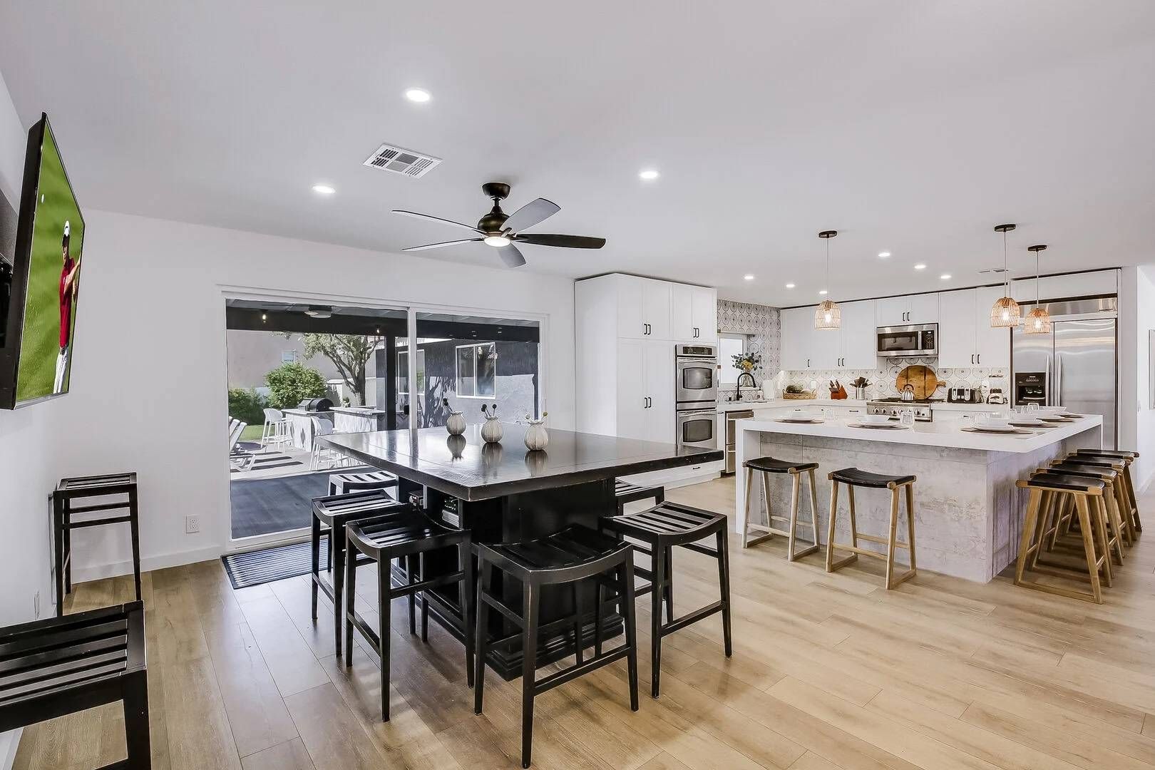A modern kitchen with a central island, bar stools, and a view of the outdoors.