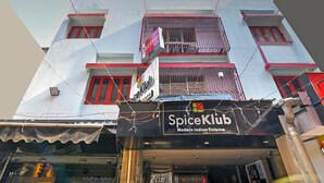 Een gebouw met meerdere balkons en een bordje met de tekst 'SpiceKlub Modern Indian Cuisine'.