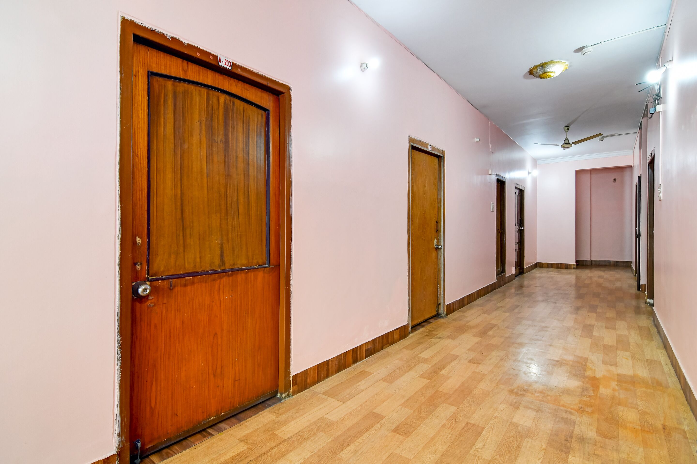 A hallway with wooden doors and a checkered wooden floor.