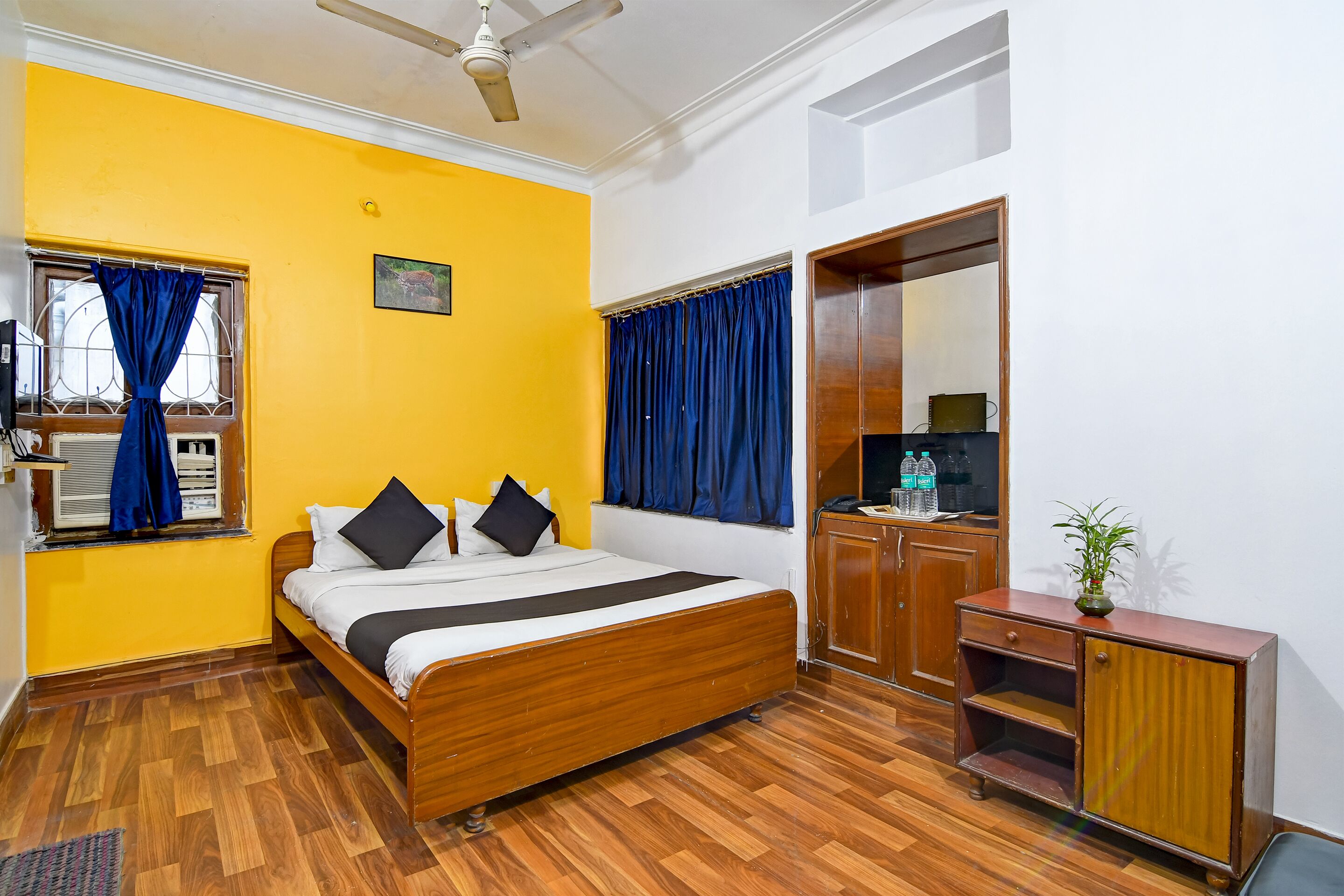 Un dormitorio con una cama de madera, un armario y una ventana con cortinas azules.