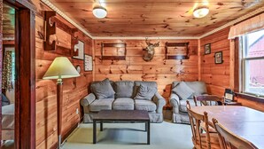 A cozy cabin interior with a sofa, a dining table, and a mounted deer head on the wall. - Charming 3-bedroom cabin in serene Solon with free fiber WiFi (Solon)