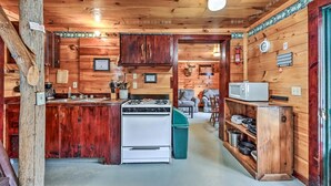 A wooden cabin interior with a kitchen area featuring a stove, sink, and cabinets. - Charming 3-bedroom cabin in serene Solon with free fiber WiFi (Solon)