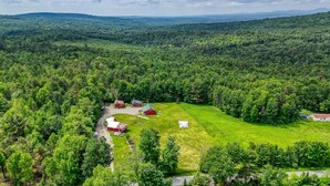 A rural property with a large green field, a red barn, and a white house. - Charming 3-bedroom cabin in serene Solon with free fiber WiFi (Solon)