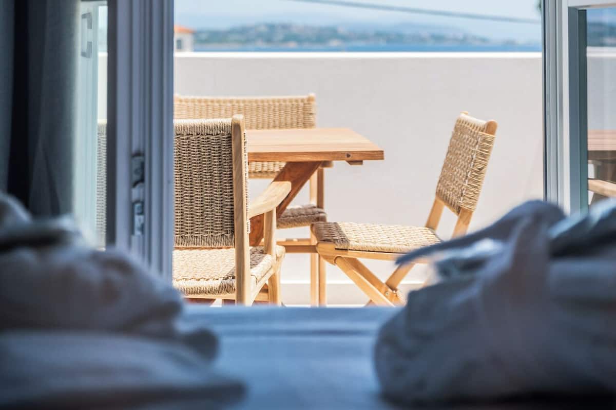 Una habitación con un ventanal grande, muebles de mimbre y vista al mar.