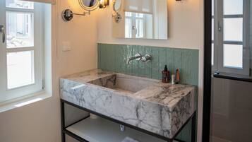 A bathroom with a marble sink, green wall paneling, and two wall-mounted mirrors.