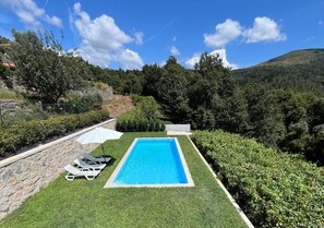A rectangular swimming pool with a stone wall on one side, surrounded by well-maintained grass and hedges. - Quinta da Vinha Velha · Villa with private pool & views in Minho (Viana do Castelo)