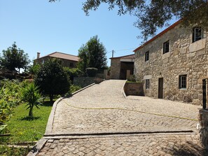 A stone building with a cobblestone path leading up to it, surrounded by greenery and trees. - Quinta da Vinha Velha · Villa with private pool & views in Minho (Viana do Castelo)