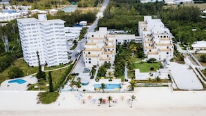 An aerial view of a coastal hotel with multiple buildings, a beach, and a swimming pool.