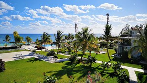 A resort with a well-maintained lawn, palm trees, and a view of the ocean.