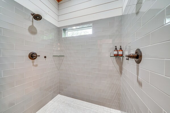 A modern shower with a glass enclosure, white tiled walls, and a small window. - Creekside Cabin w/ Views & Hot Tub in Broken Bow (Broken Bow)