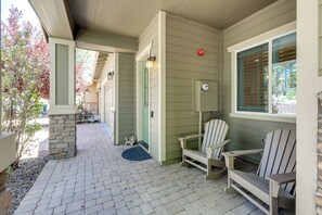 Eine überdachte Veranda mit Adirondack-Stühlen, einer Steinsäule und einer blauen Fußmatte.