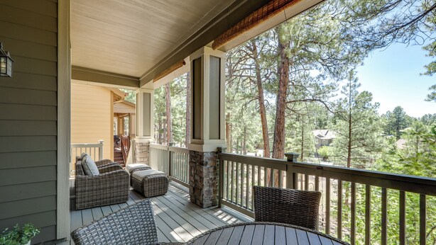 A wooden deck with wicker furniture and a stone pillar, overlooking a forested area. - Tasteful Flagstaff Townhome w/ 2 Furnished Decks (Flagstaff)