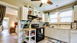 A modern kitchen with white cabinetry, a black stove, and a ceiling fan. - Walk Downtown: Inviting Apartment in Greensboro! (Greensboro)