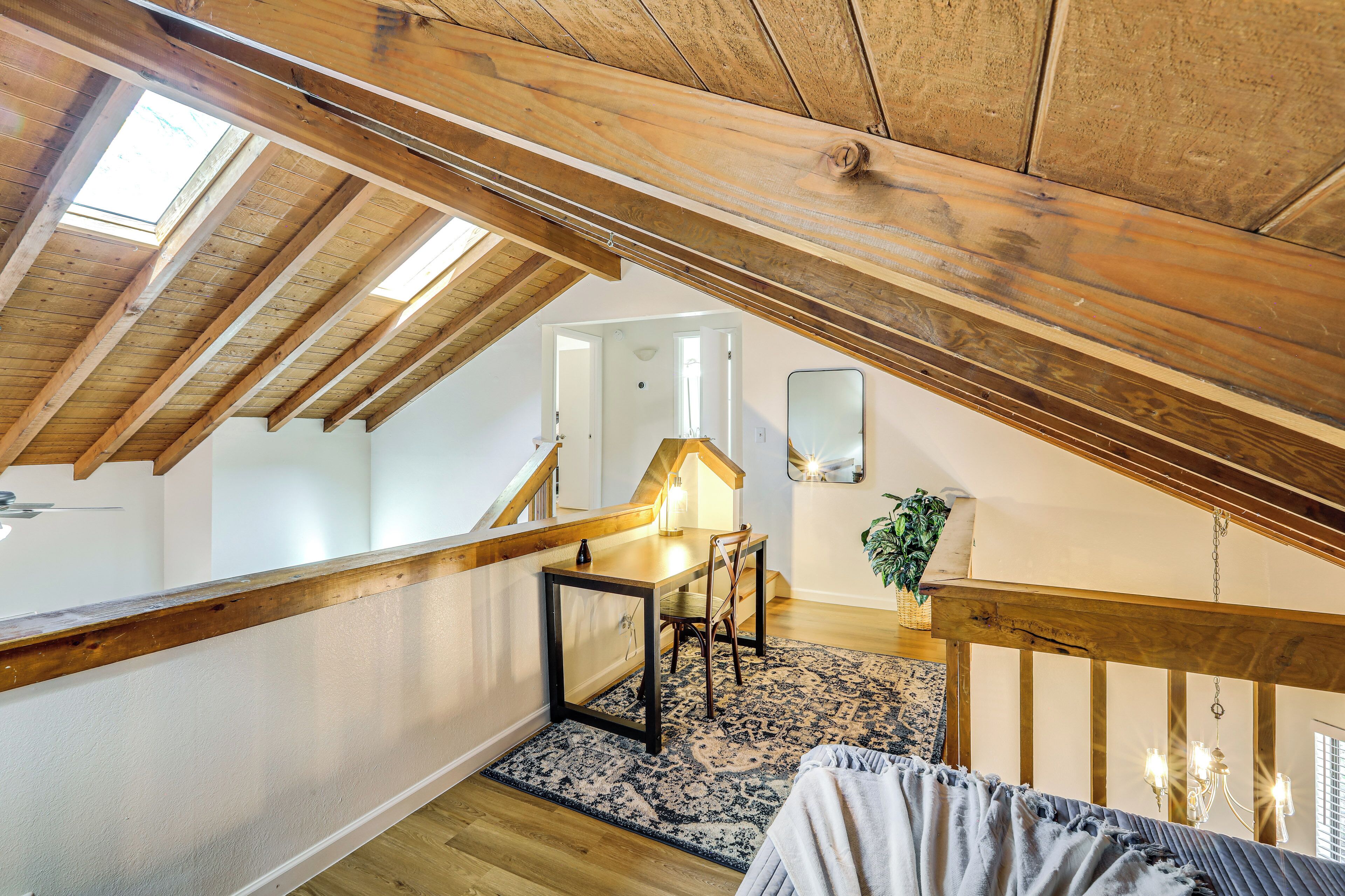 A loft bedroom with a wooden ceiling, a dining area with a table and chairs, and a staircase.