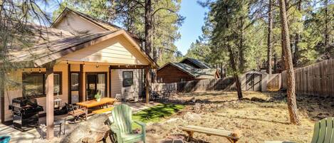 A cabin with a covered patio, outdoor seating, and a fire pit.