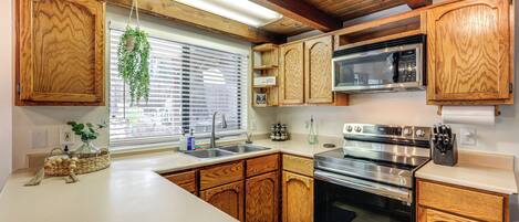 A kitchen with wooden cabinets, a microwave, and a stove.